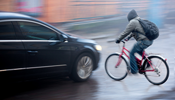 A man in a bicycle almost getting hit by a car